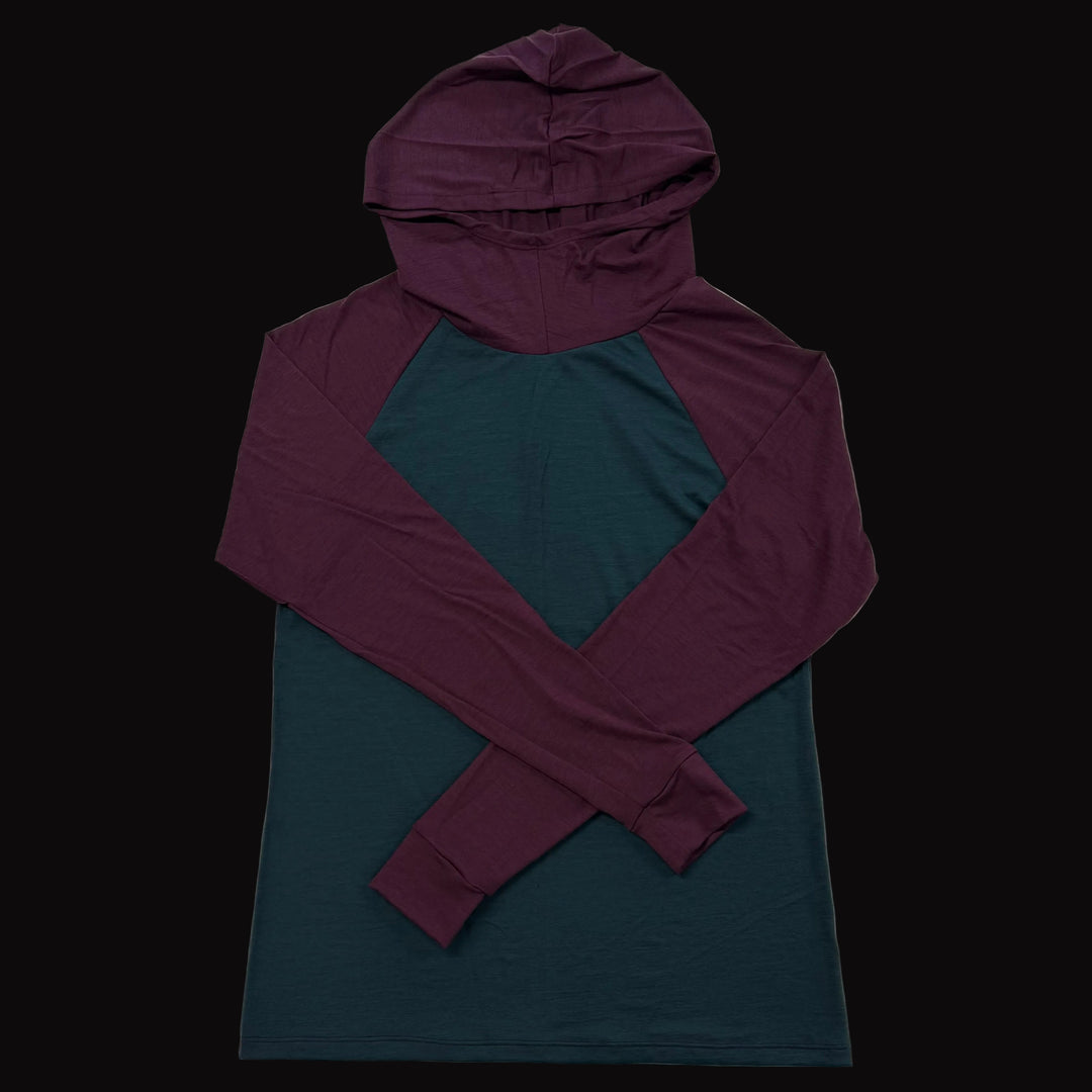 A long-sleeve hooded shirt laid flat on a light gray background, featuring a dark teal body and a contrasting deep purple hood and sleeves.