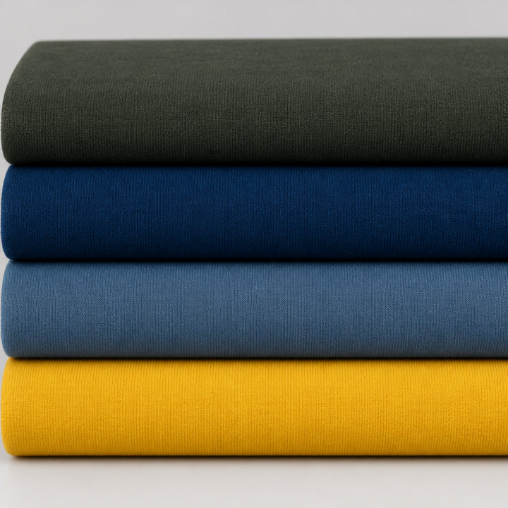 Three folded fabric or textile rolls stacked horizontally, showing solid colors: dark olive green on top, deep blue in the middle, and mustard yellow on the bottom.