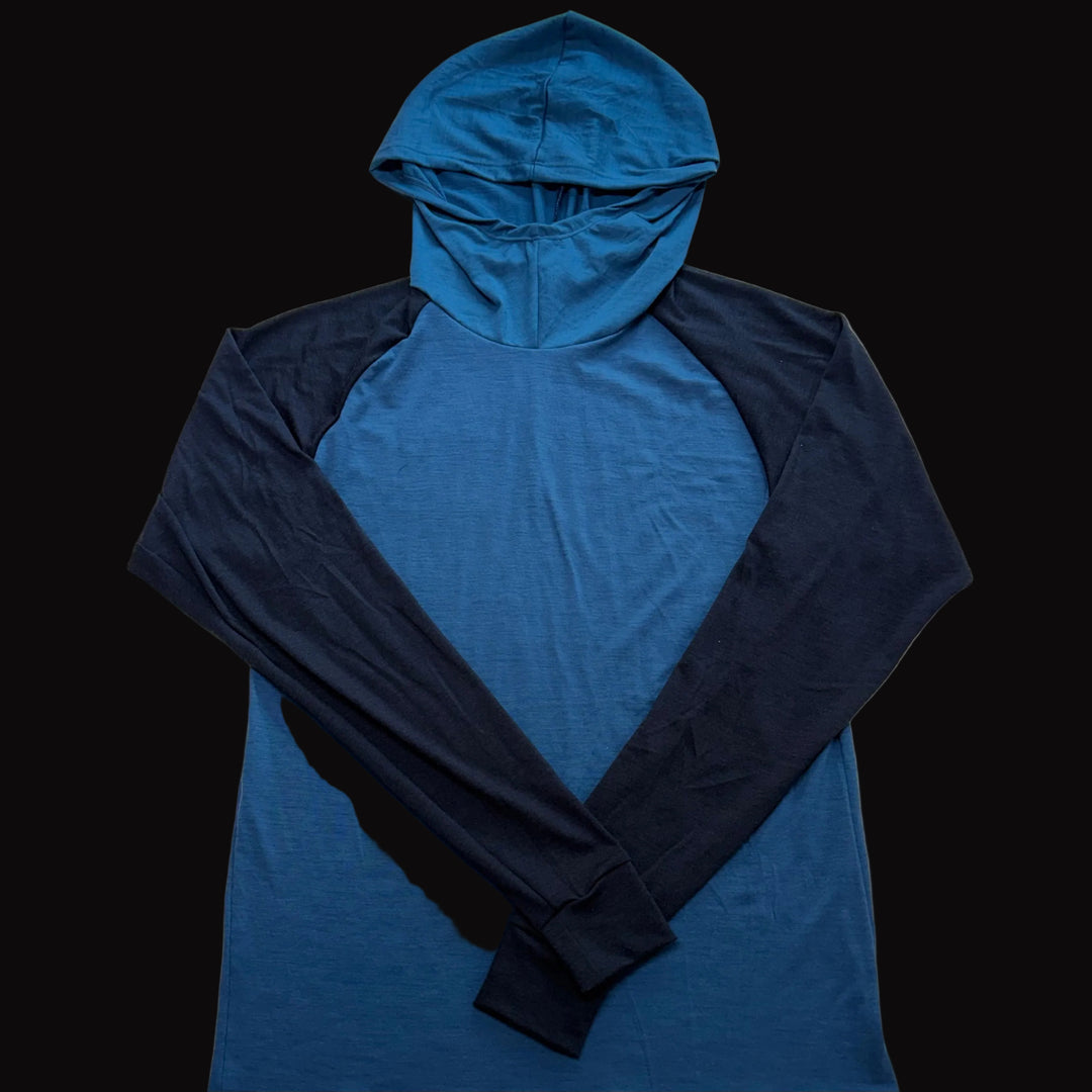 A long-sleeve hooded shirt laid flat on a black background, featuring a bright blue body and hood with dark navy sleeves.